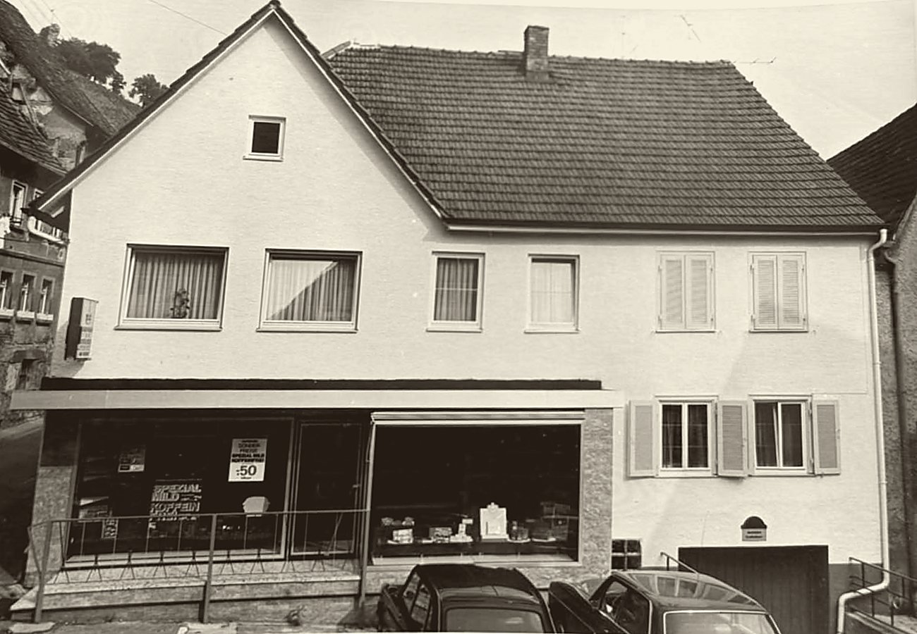 Der Laden in der Hirschgasse mit großem Schaufenster; davor parken Autos.